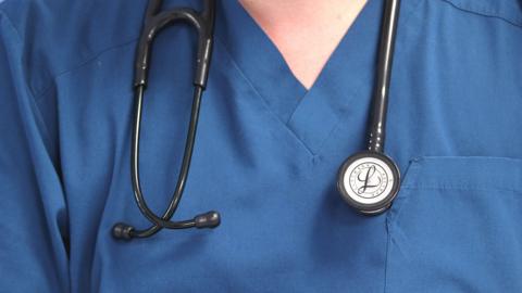 A doctor wearing a stethoscope. They have blue clothes on.