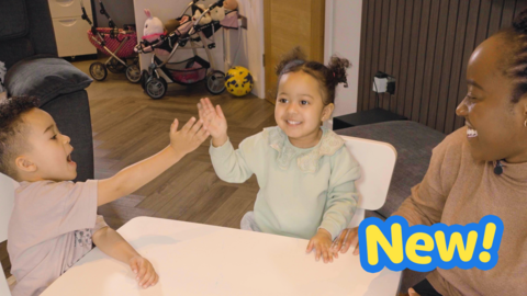 Family sit around a small table - a young boy and young girl high five.