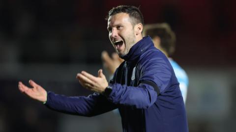 Walsall head coach Mat Sadler holds his arms out in delight after winning a game