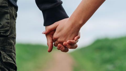 A couple holding hands on a country lane 