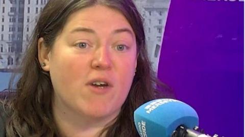 Emily Spurrell speaking into a microphone in a studio at BBC Radio Merseyside, while on air