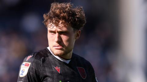 West Bromwich Albion defender Callum Styles looks to his right during a game. He is wearing a black club away shirt.