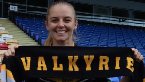 Remi Wilton holds up a Valkyrie scarf on her presentation to fans