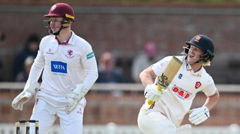 Jordan Cox appears to be in discomfort after playing a shot for Essex, while Somerset wicketkeeper James Rew stands behind the stumps