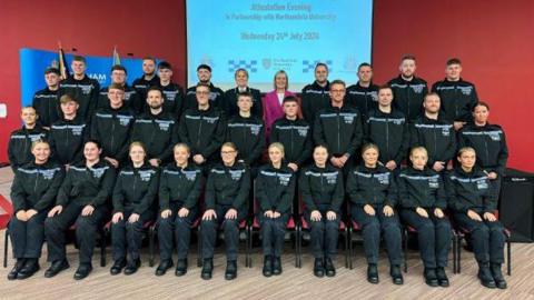 A group of new police recruits with their hands on their knees 