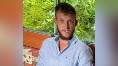 A man with a blue shirt and short hair and a beard