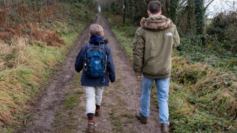 A boy and a man walk on a path in Somerset