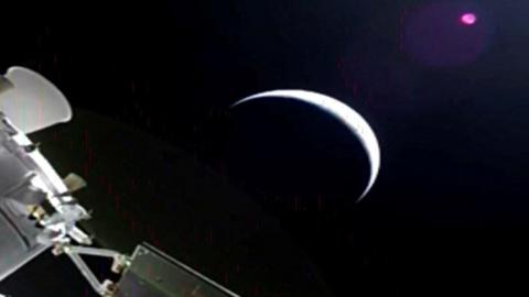 A sliver of the moon and parts of the orion spacecraft off to the side.