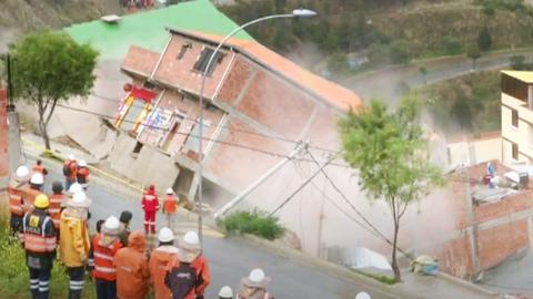 Rescuers watch a house collapse