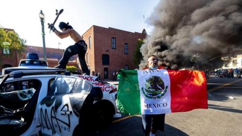 Image shows a demonstrator hitting a Waymo self-driving car with his skateboard during a protest against federal immigration sweeps, in downtown Los Angeles on 8 June 2025
