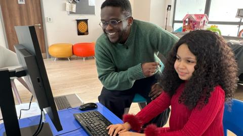Newsround's De-Graft Mensah with a young girl, Rama, playing Minecraft