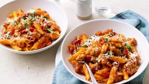 Two bowls of sausage and penne pasta.