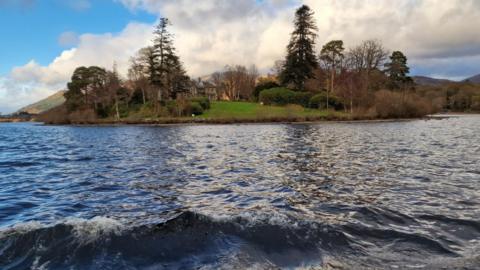 The house on Derwent Island, seen from a boat sailing on Derwentwater.