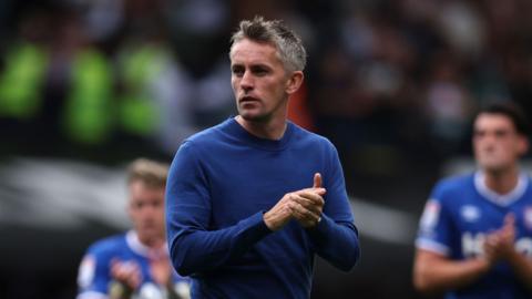 Ipswich Town manager Kieran McKenna has his hands together in a clapping motion and has a pensive look on his face