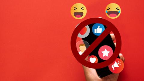 Emojis float over a smartphone, held by a hand against a red background. A stop sign is slapped over the top of the image.