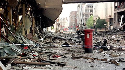 Scenes of devastation following the IRA bomb in Manchester city centre on 15 June 1996. Rubble and debris cover the streets while a red postbox stands apparently unscathed.