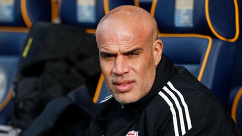 Marcus Bignot sat in the dugout watching the match action during a Swindon game away at Shrewsbury Town