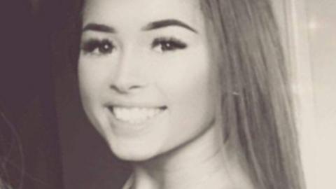 Grace Robinson is smiling at the camera in a black and white photo. She has dark eyes and long hair