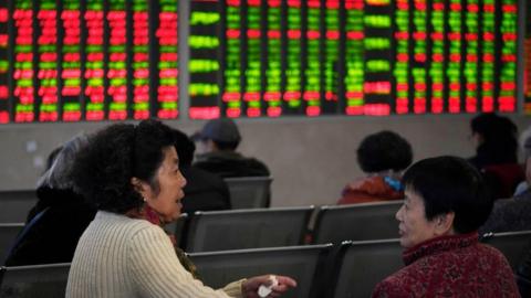 Women sit in front of stock boards in China