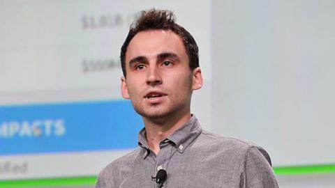 Nikita Bier, wearing a grey, button-up shirt with a microphone attached, speaks on-stage at TechCrunch Disrupt in 2013.