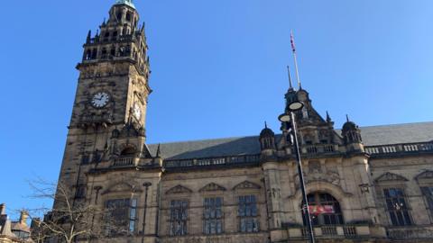 The outside of Sheffield town hall which is a Victorian, gothic style building with a clock tower, large windows and ornate balustrades