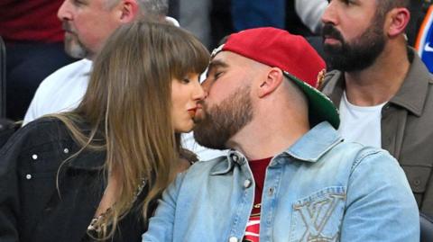 Singer Taylor Swift and Travis Kelce of the Kansas City Chiefs kiss during Game Three between the New York Knicks and the Cleveland Cavaliers in the NBA Eastern Conference Finals at Rocket Arena on May 23, 2026 in Cleveland, Ohio. 