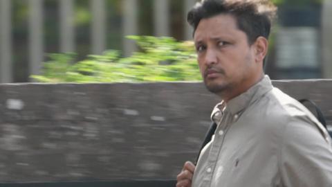 A man walks quickly past a camera. 
