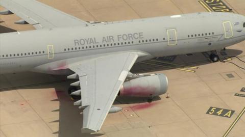 Red paint on the engine and wing of a grey RAF plane, which has the words Royal Air Force on its body. 