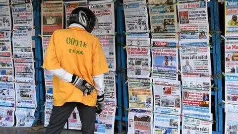 Motorcycle taxi member looks at newspapers at the entrance to the National Hospital and University Centre (CNHU) in Cotonou on April 6, 2021