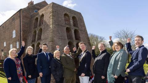 A line of VIPs gathered in a line to celebrate at a blast furnace that is now a museum