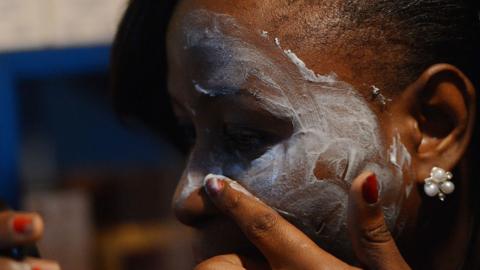 A beautician in Nairobi, Kenya shows how to rub skin-lightening cream, on March 18, 2015.