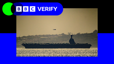 USS Gerald R Ford in the Strait of Gibraltar with a helicopter flying in the distance framed by BBC Verify blue branding 