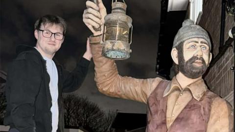 Kyle Wilcock with his left hand is touching the right arm of the statue