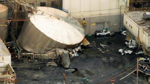 The ruptured tank, with crushed cars in the foreground