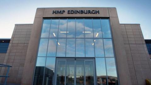 A large modern building with a glass frontage. There is a sign above the glass saying HMP Edinburgh