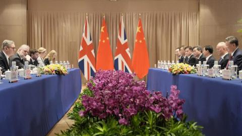 British Prime Minister Keir Starmer attends a bilateral meeting with President Xi Jinping - their teams sit opposite each other, with UK and Chinese flags between them