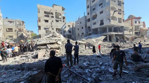 People gather at the site of an Israeli strike in Beit Lahia, northern Gaza Strip. Photo: 20 October 2024