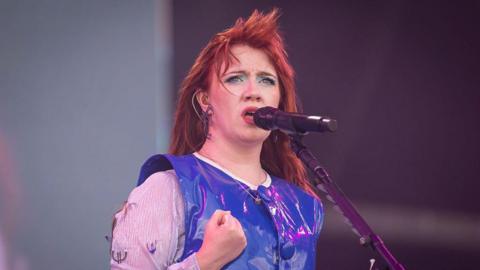 CMAT, dressed in a bright and shiny blue top, sings during day three of Glastonbury festival 2025 at Worthy Farm in Pilton, Somerset. 