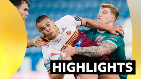 Tui Lolohea of Huddersfield is tackled by Alex Walmsley and George Delaney of St Helens