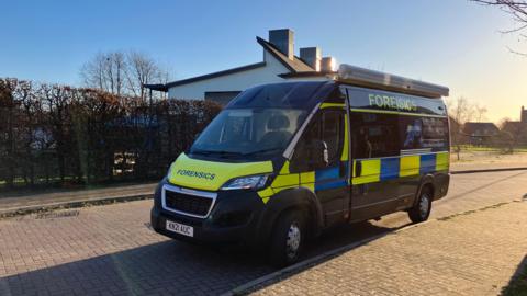 A forensic van parked on a residential street on a sunny day