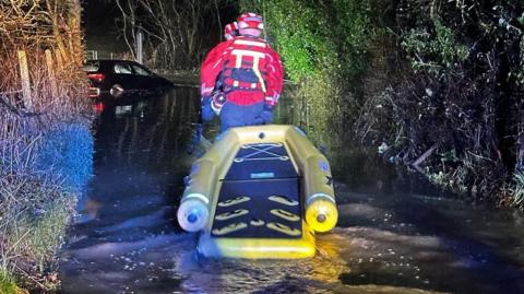 Firefighters rescuing a woman from a car in flood water 