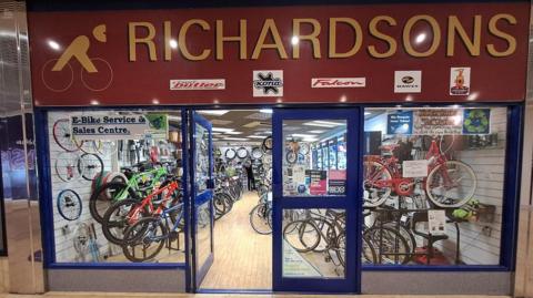 A shop window with cycles inside the store and a red shop sign which reads Richardsons
