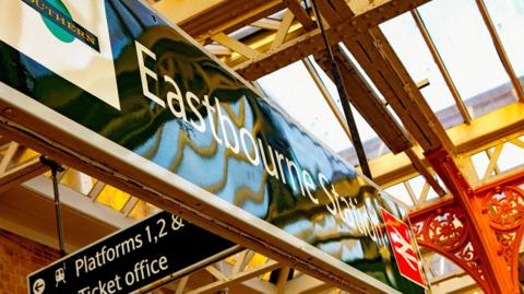 A sign for Eastbourne station with a Southern logo on the side. 