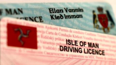 Two Isle of Man driving licences on top of each other - one on top is pink, the other is blue.
