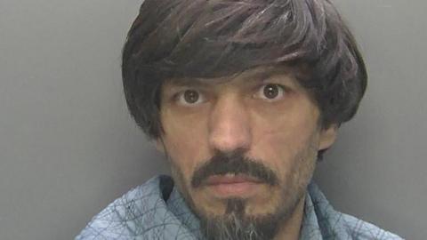 Ajmel's custody image. He is a man with longish black hair and a small beard.