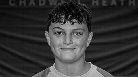 A black and white image of Oscar - a young teenager smiling at the camera wearing a T-shirt.