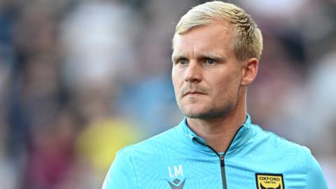 Oxford United head coach Liam Manning looking tense on the touchline during a League One match.