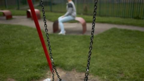 A teenage girl sits near a swing