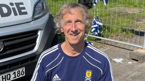 Jim Taggart in a Scotland shirt beside his camper van