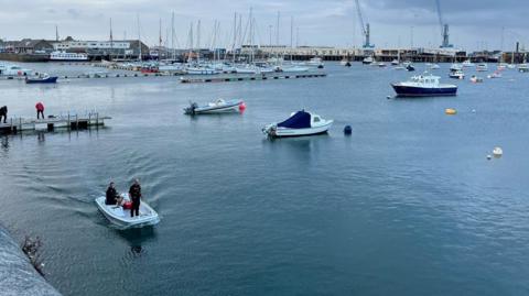 Two police officers pilot a small boat in a harbour